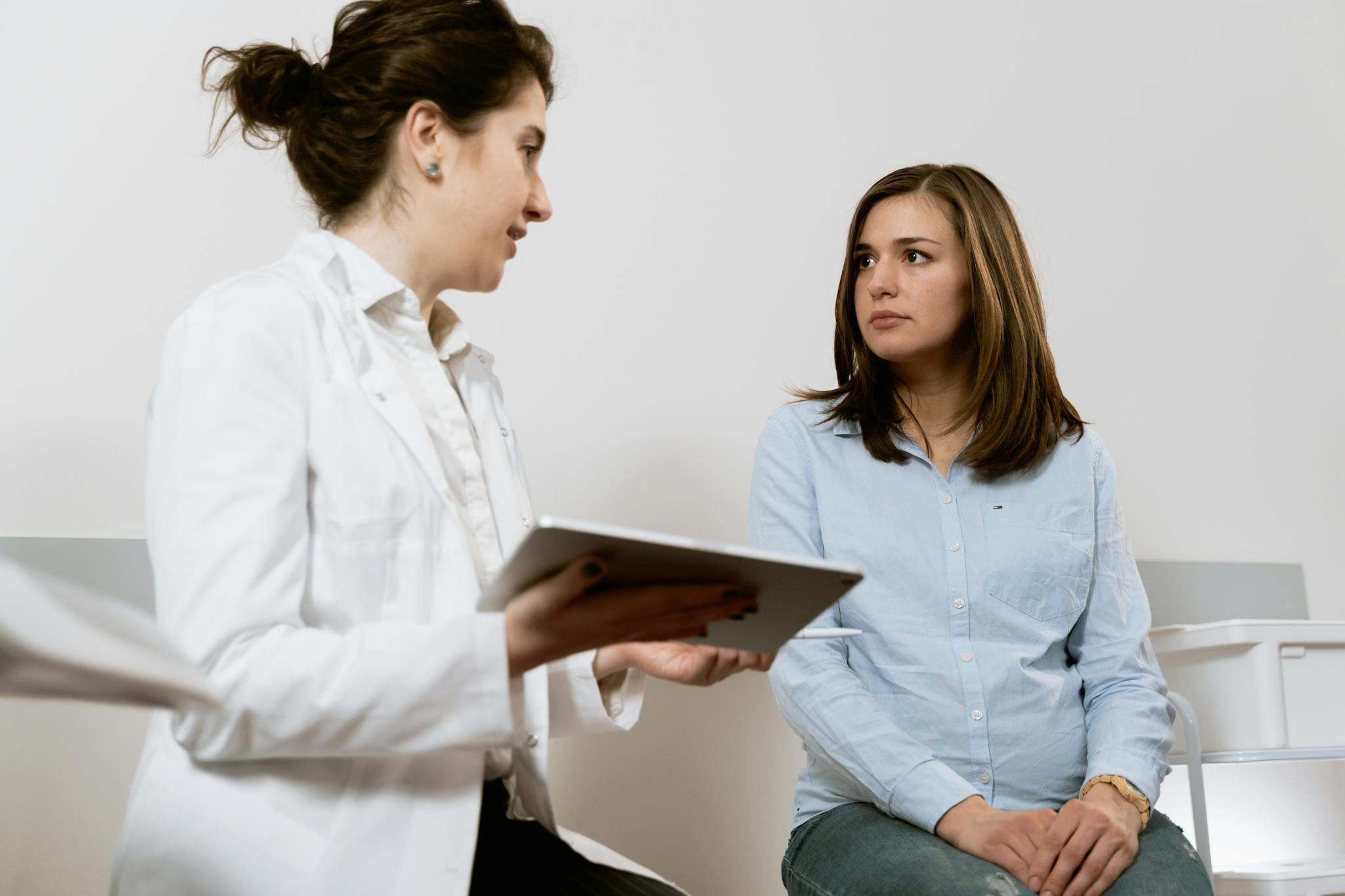 A doctor consults with a pregnant patient discussing healthcare options in a medical facility. Emotional Changes During Pregnancy and How to Cope