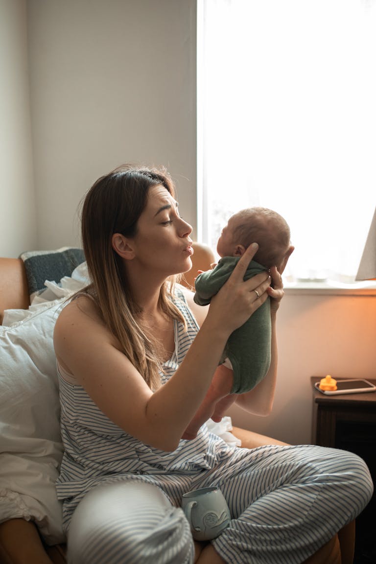 A tender moment of a mother holding her newborn baby by a bright window indoors. How to Heal After a C-Section: Physical and Emotional Recovery