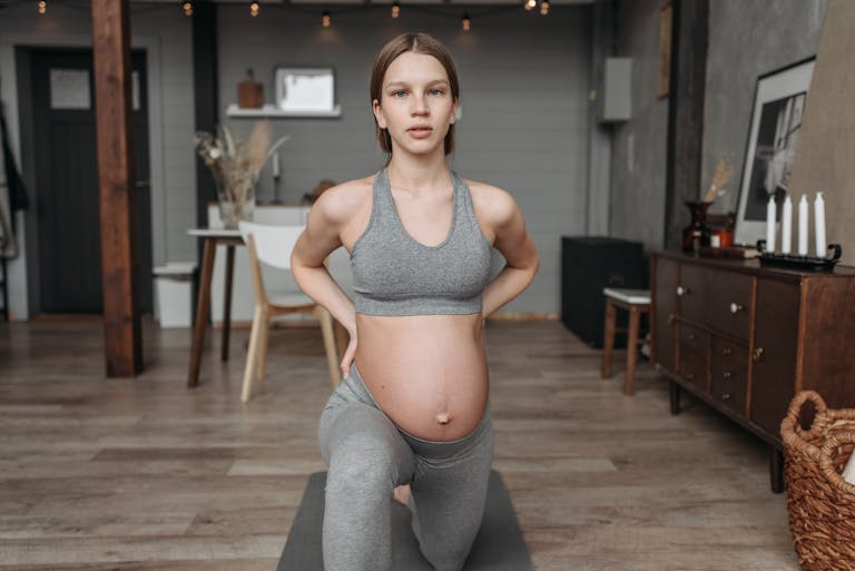 Pregnant woman in activewear doing yoga at home, promoting wellness and prenatal fitness. Top 5 Prenatal Exercises You Can Do at Home