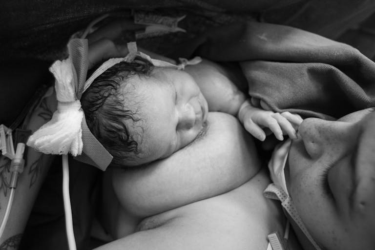 Tender black and white photo capturing the intimate bond between mother and newborn during skin-to-skin contact. Postpartum Body Changes No One Talks About Postpartum Body Changes No One Talks About