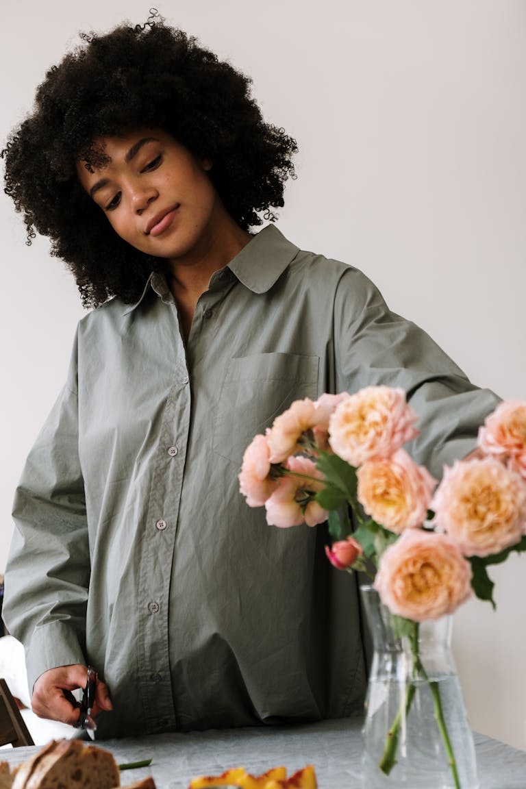 A beautiful pregnant woman arranging roses in a vase indoors, exuding tranquility and joy. Pregnancy Mood Swings: Understanding the Rollercoaster of Emotions