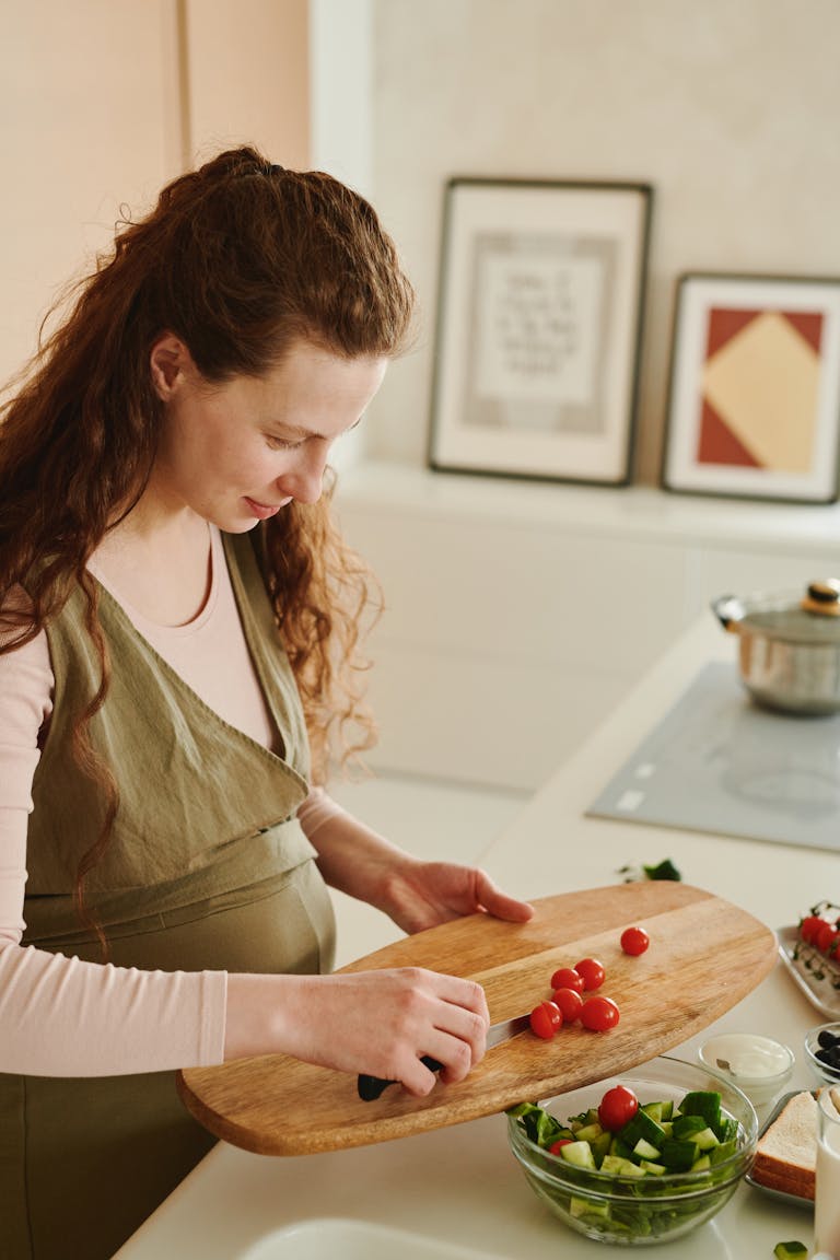 Expectant mother chopping vegetables for a fresh salad in her kitchen. 7 Easy and Nutritious Pregnancy Food Recipes You’ll Love