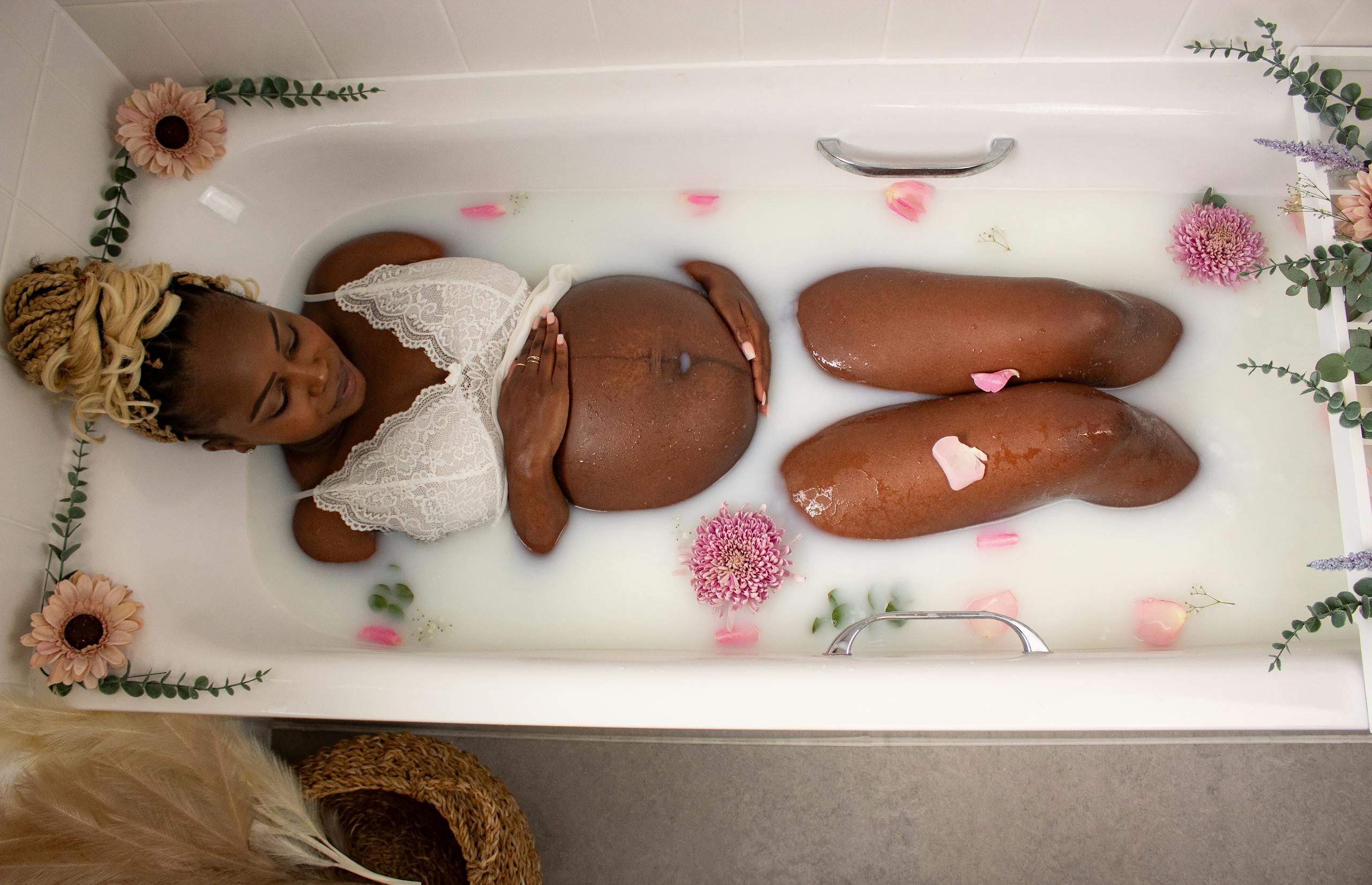 Pregnant woman enjoying a relaxing floral milk bath for a serene maternity experience. 🌸 Mom-To-Be Pampering Guide: Because You Deserve It, Mama!